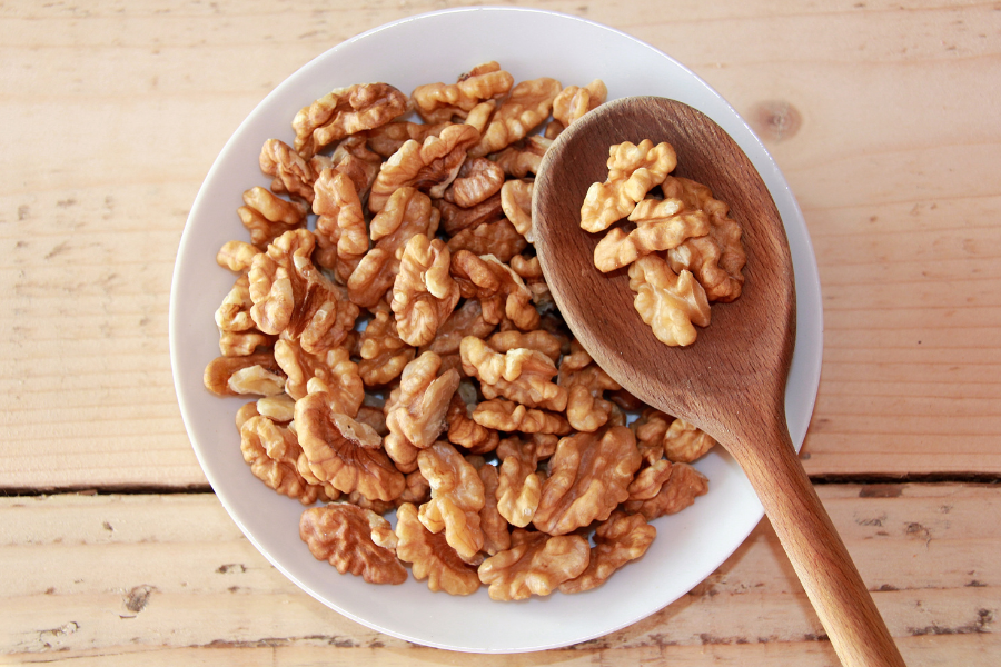 a bowl of walnuts with a wooden spoon