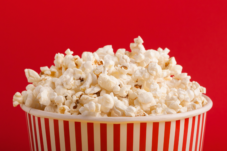 a tub of popcorn with a red background