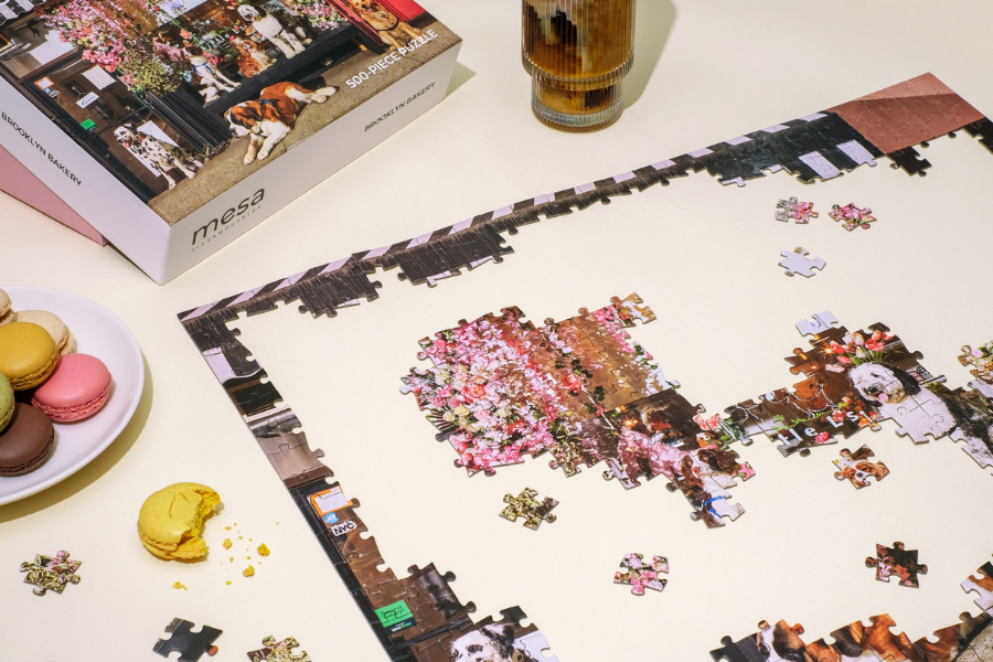 a jigsaw puzzle being completed with macaroons and coffee next to it