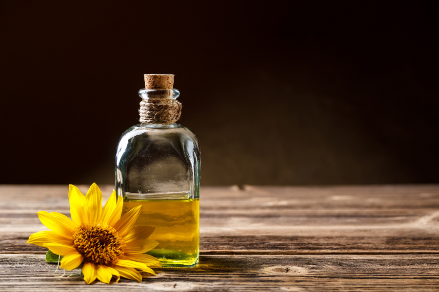 sunflower oil next to a sunflower on a wooden table